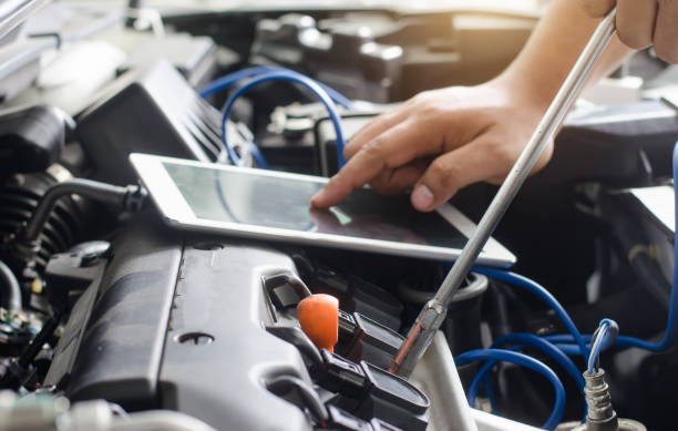 Mécanicien qui effectue des réparations électroniques sur une voiture